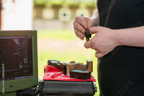 A skilled female athlete, known for her dedication and accuracy, pulls out a pistol during a sports shooting training session, demonstrating focus and precision in her practice routine. photo