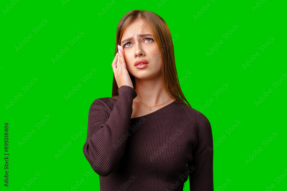 Young Woman With Brown Hair Wearing A Maroon Sweater Looks Up And Touches Her Forehead While Standing Against A Green Screen Young Woman With Brown Hair Wearing A Maroon Sweater Looks Up And Touches Her Forehead While Standing Against A Green Screen