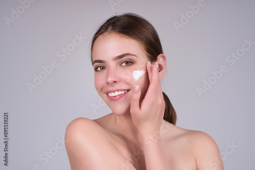 Fotografie Beautiful woman applying moisturizer cream her face