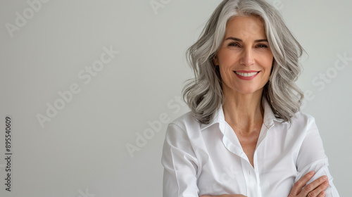 Handsome woman 50s mid age beautiful physically fit well groomed senior model grey hair stylish smiling Healthy face skin care skincare hair care fitness dental off center copy space gray background