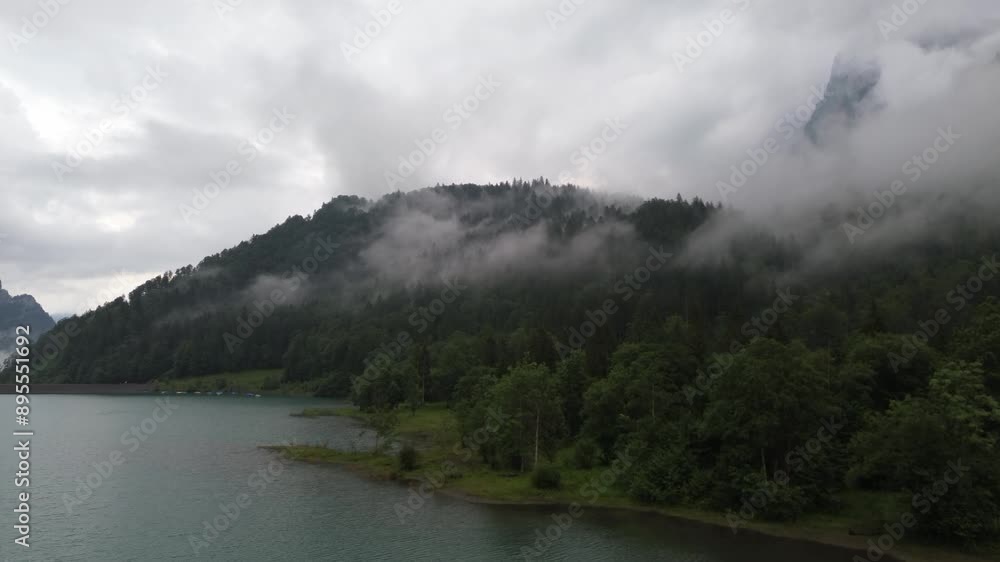 Drone shot of an Alpine lake surrounded by mountains with low clouds in Switzerland Klontalersee Drone shot of an Alpine lake surrounded by mountains with low clouds in Switzerland Klontalersee