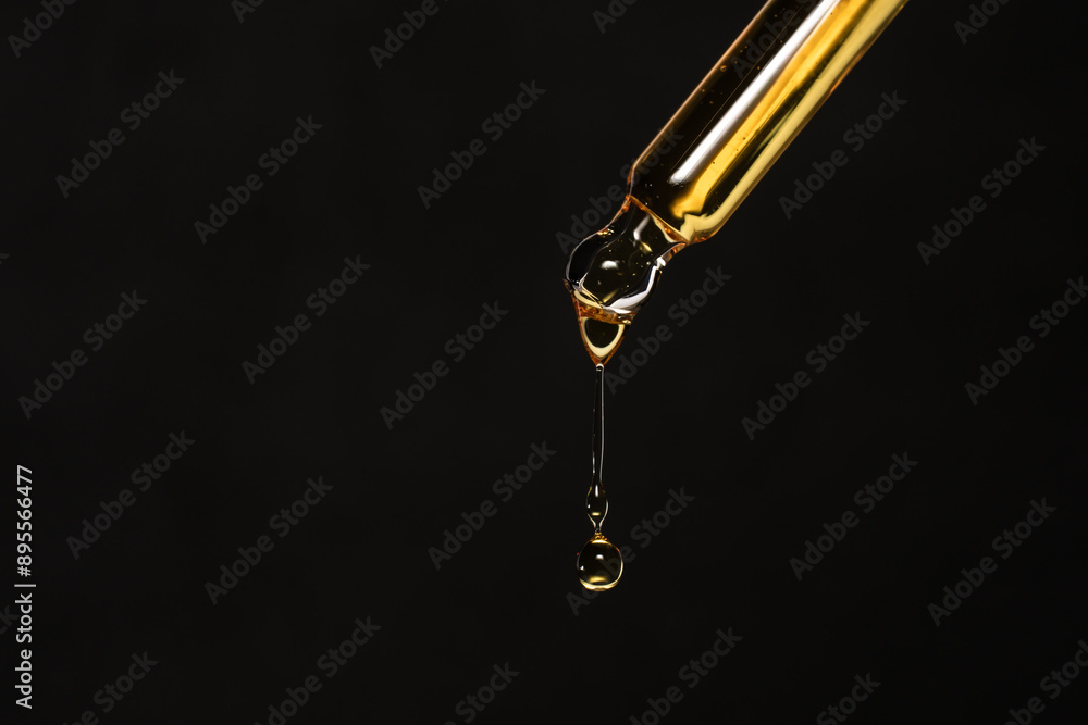 Macro photo of pipette with dripping golden liquid on black background, care product. Macro photo of pipette with dripping golden liquid on black background, care product.