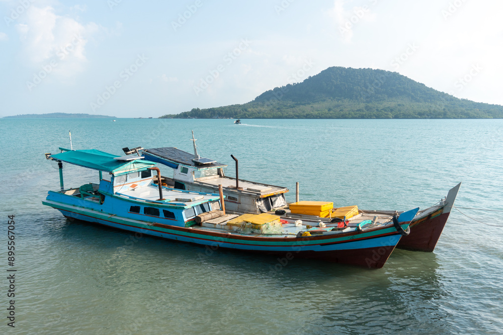 two fishing boats docked in the harbor with views of the hills two fishing boats docked in the harbor with views of the hills