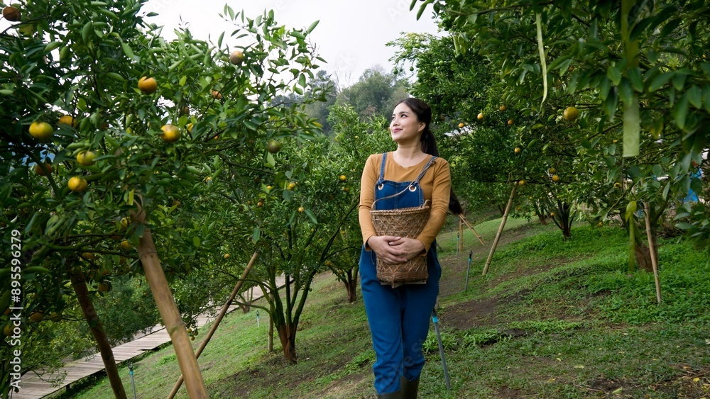 Young Asian woman in denim overalls holding a wicker basket, standing ...