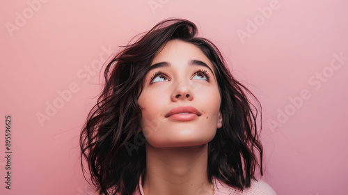 Woman with hopeful expression looking upwards on pastel background