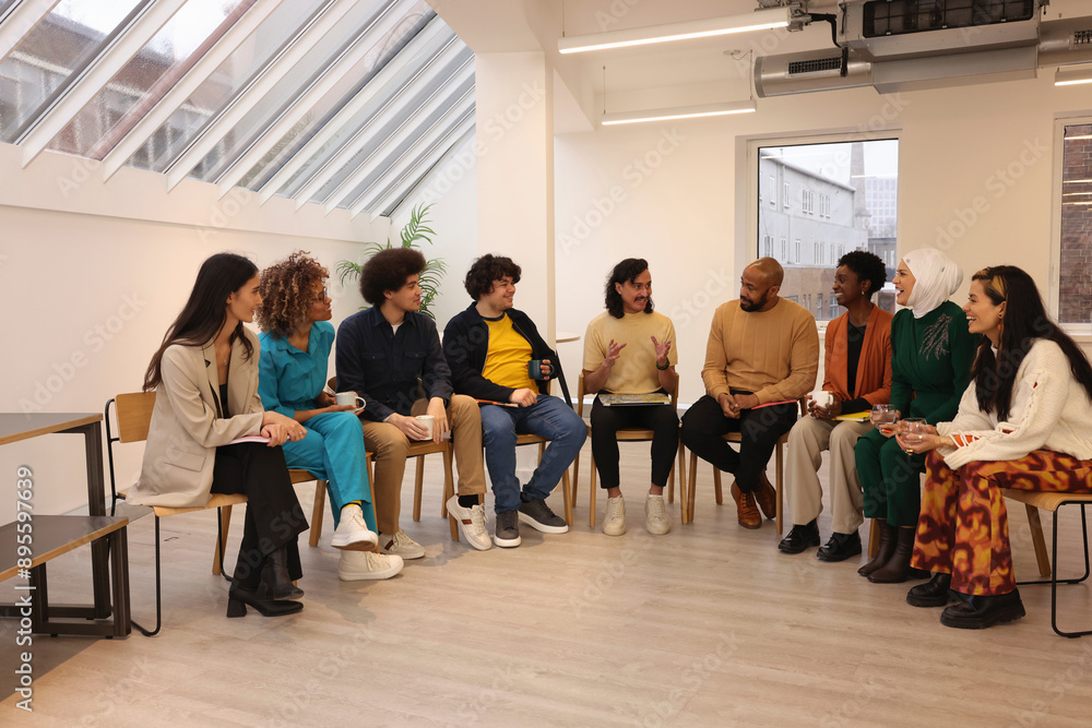 Creative workers in office;�Multiethnic�group of creative workers sitting and talking in modern office Creative workers in office;�Multiethnic�group of creative workers sitting and talking in modern office