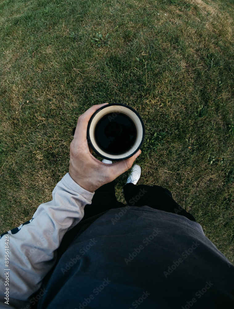 a man holds a cup of coffee in his hand in nature a man holds a cup of coffee in his hand in nature