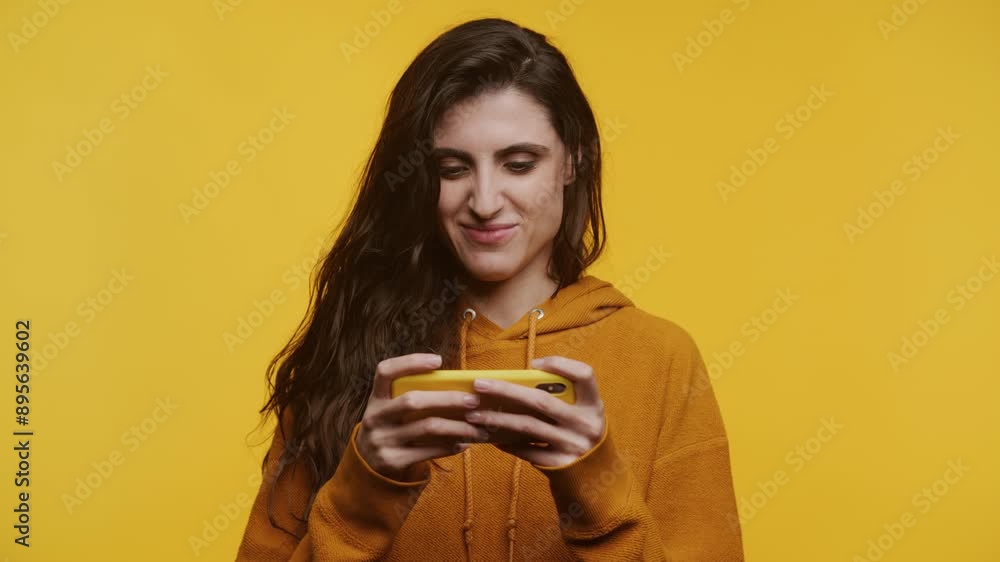 Happy Woman Playing on Smartphone on Yellow Background Happy Woman Playing on Smartphone on Yellow Background