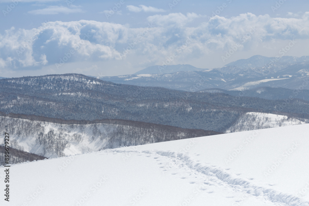 Line of footprints leading over snowy mountain ridge winter landscape in Hokkaido Japan Line of footprints leading over snowy mountain ridge winter landscape in Hokkaido Japan