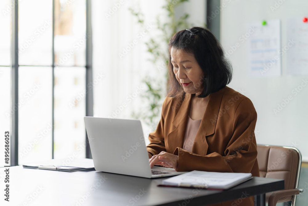 Asian female senior entrepreneur using her laptop at home Asian female senior entrepreneur using her laptop at home