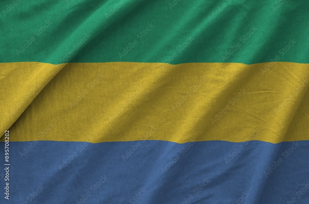 Gabon flag depicted on folded wavy fabric of old cloth close up Gabon flag depicted on folded wavy fabric of old cloth close up