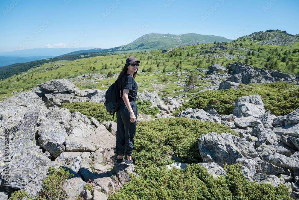Traveler Woman standing on a rocks in the summer mountain .Vitosha Mountain ,Bulgaria Traveler Woman standing on a rocks in the summer mountain .Vitosha Mountain ,Bulgaria