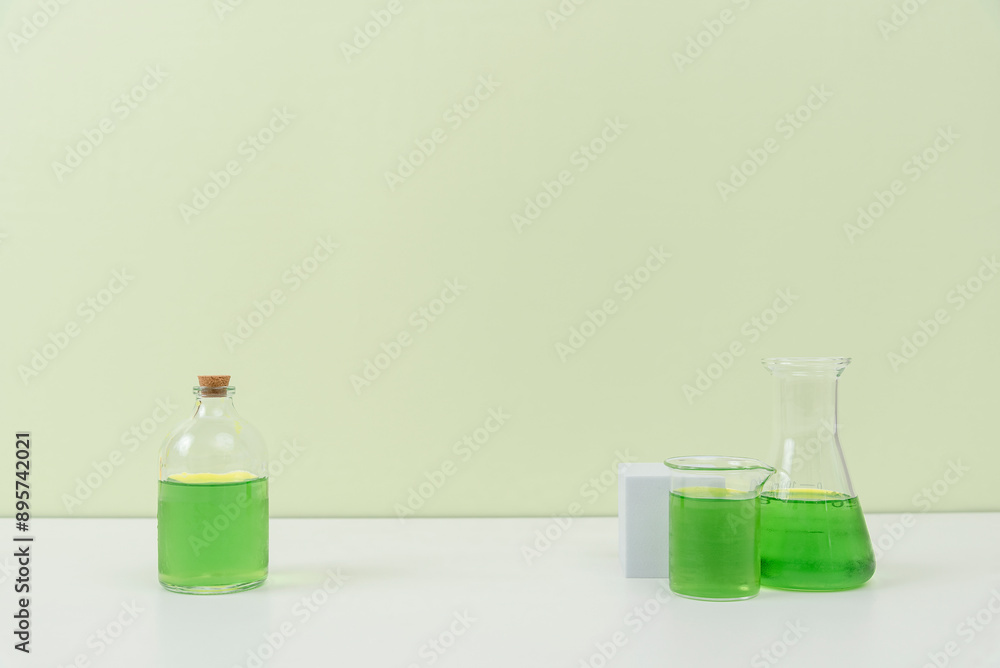 Assorted Laboratory Glassware with Green Liquid on White Surface Assorted Laboratory Glassware with Green Liquid on White Surface