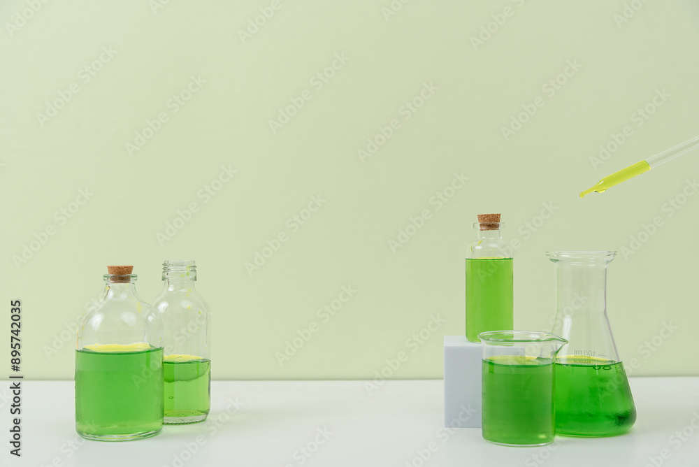 Assorted Laboratory Glassware with Green Liquid on White Surface Assorted Laboratory Glassware with Green Liquid on White Surface