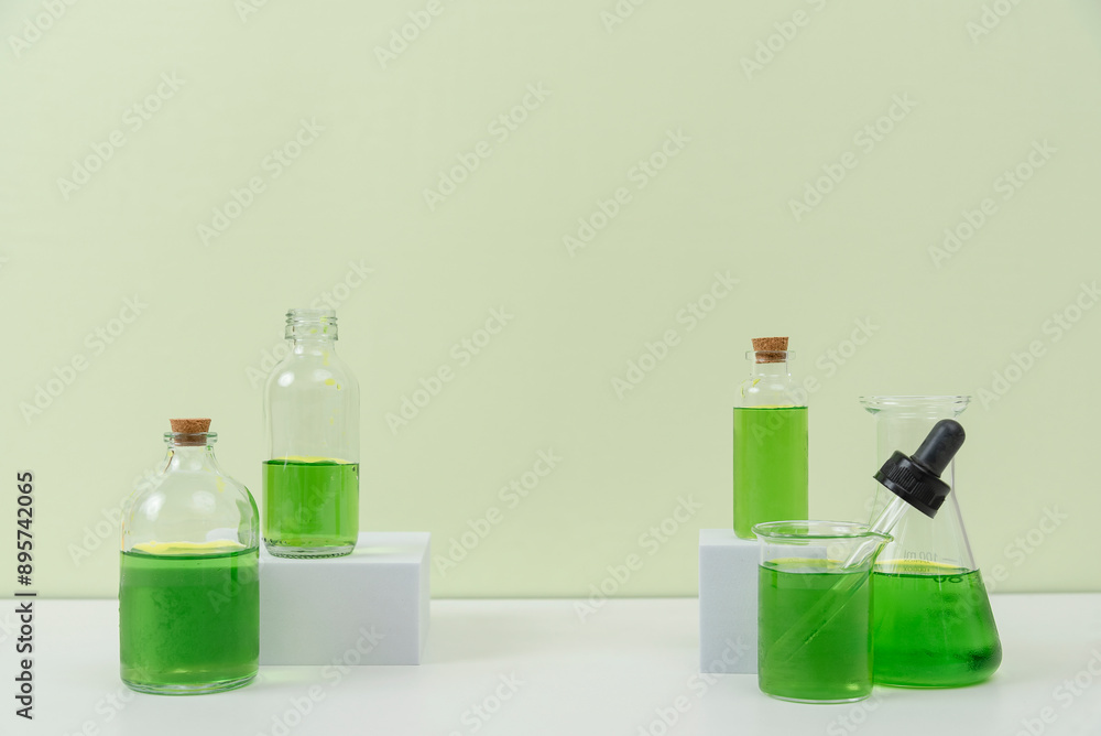 Assorted Laboratory Glassware with Green Liquid on White Surface