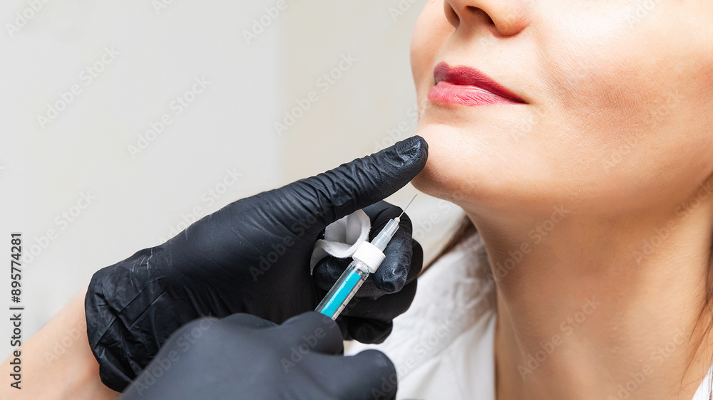 Plastic surgery. Young woman receiving injection in the chin at beauty clinic, closeup, copy space, banner size Plastic surgery. Young woman receiving injection in the chin at beauty clinic, closeup, copy space, banner size
