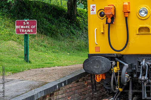 Front of a stationary diesel train alongside a beware of trains sign at the Watercress Line, Alresford, Hampshire, UK photo