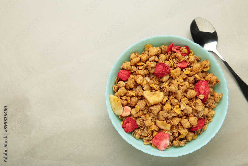 Granola with strawberries in a bowl on light background. Granola with strawberries in a bowl on light background.