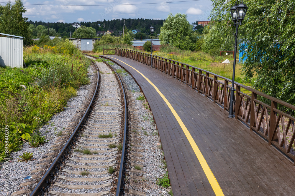 An empty railway track turning left along a station platform