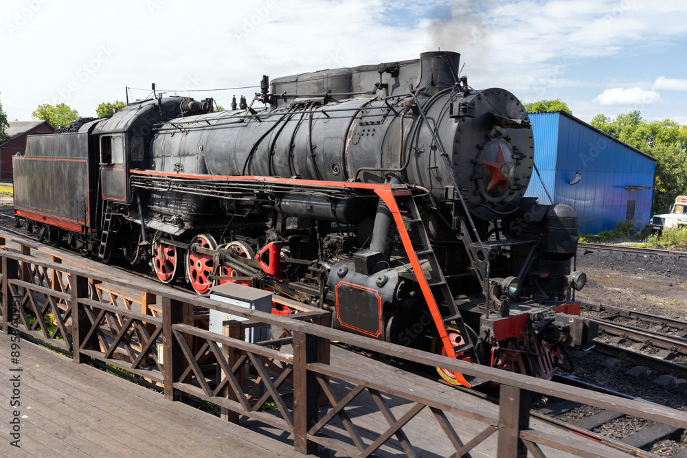 Naklejka premium Black retro steam locomotive from USSR times is near the station