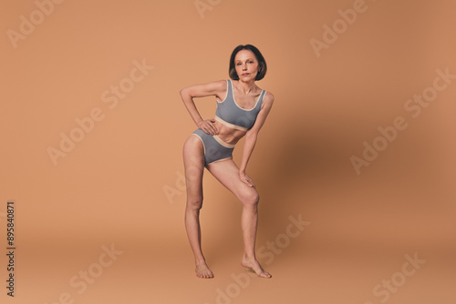 No filter photo of charming lovely woman posing athletic sporty shape isolated on beige color background © deagreez