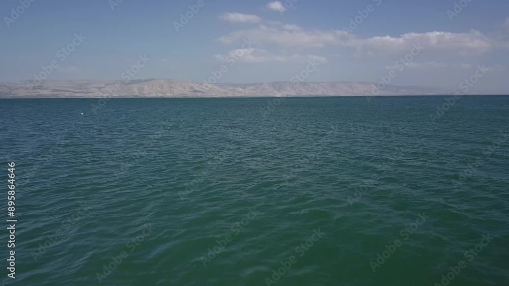Fast drone flight over Sea of Galilee in Israel with mountains and cloudy sky on the horizon. Above angle shot, proximity flight Fast drone flight over Sea of Galilee in Israel with mountains and cloudy sky on the horizon. Above angle shot, proximity flight