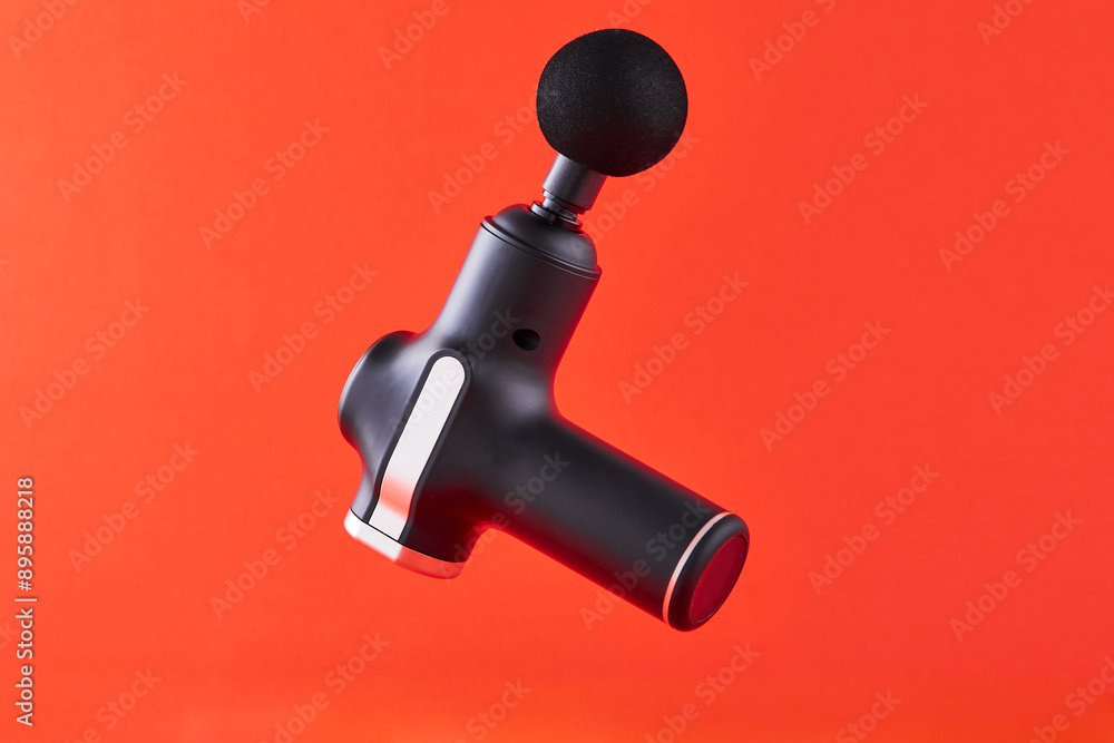 Massage gun machine or electric stimulator for massaging on orange background. Post-workout recovery tool for muscle physical therapy. Massage gun machine or electric stimulator for massaging on orange background. Post-workout recovery tool for muscle physical therapy.