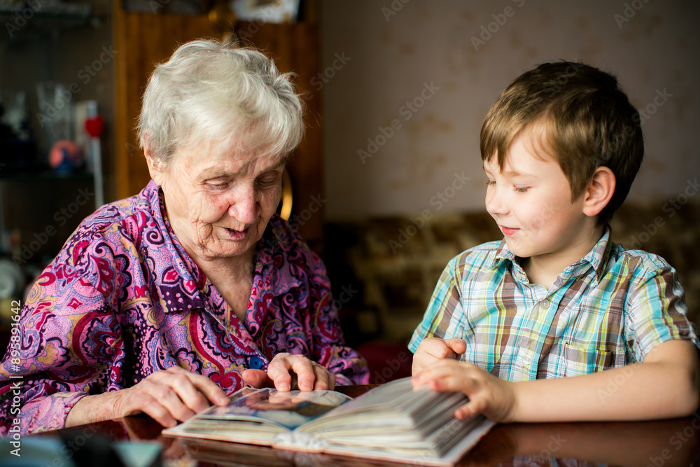 An elderly woman and her grandson looking at a photo album.