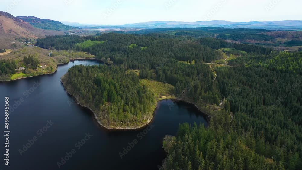 Green pine tree forest in the Trossachs National Park. Clear day on Loch Ard with rolling wooded hills. Beautiful wild landscape. Scottish Highlands, Scotland, United Kingdom. Green pine tree forest in the Trossachs National Park. Clear day on Loch Ard with rolling wooded hills. Beautiful wild landscape. Scottish Highlands, Scotland, United Kingdom.