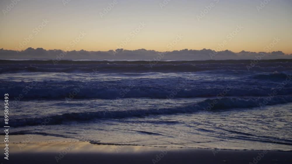 Waves of the Pacific Ocean gently roll in after sunset, their rhythmic motion reflecting the fading light and creating a serene, calming ambiance on the tranquil evening sea. Waves of the Pacific Ocean gently roll in after sunset, their rhythmic motion reflecting the fading light and creating a serene, calming ambiance on the tranquil evening sea.