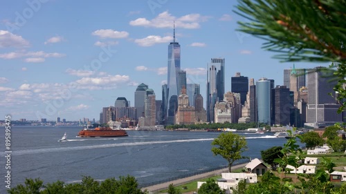 Wide shot of New York Skyline with Staten Island ferry leaving manhattan from the top of governor's island in summer.