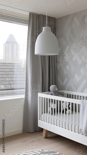 A white crib with a pink bunny toy sits on a wooden floor, next to a bed with a duvet cover