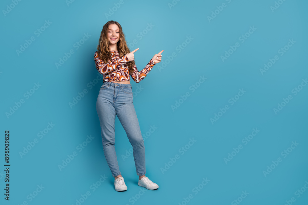 Full length photo of cheerful pretty lady dressed vintage shirt pointing two fingers empty space isolated blue color background Full length photo of cheerful pretty lady dressed vintage shirt pointing two fingers empty space isolated blue color background