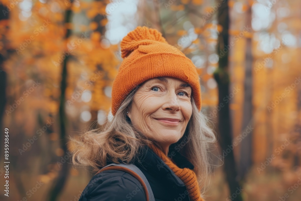 Positive cheerful woman in orange hat enjoying walk outdoors in autumn forest. Happy older woman Positive cheerful woman in orange hat enjoying walk outdoors in autumn forest. Happy older woman