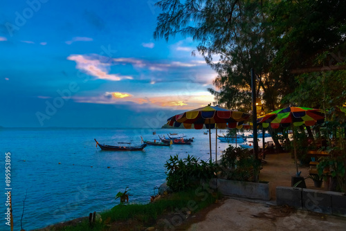 Colourful Skies Sunset over Rawai Beach in Phuket island Thailand. Lovely turquoise blue waters  lush green mountains colourful skies and beautiful views of long tail Boats 
