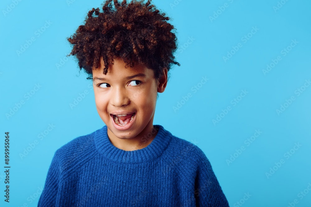 Excited young african american boy with mouth wide open against a vibrant blue background expressing pure joy and wonder Excited young african american boy with mouth wide open against a vibrant blue background expressing pure joy and wonder