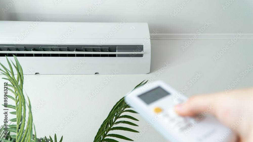 Person adjusting the temperature of the room with the remote control. Office indoors Person adjusting the temperature of the room with the remote control. Office indoors