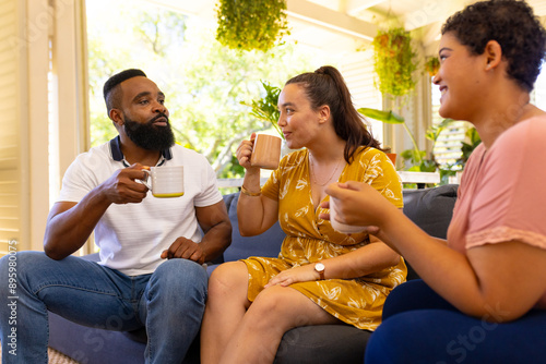 Friends sitting on couch, drinking coffee and chatting at home photo