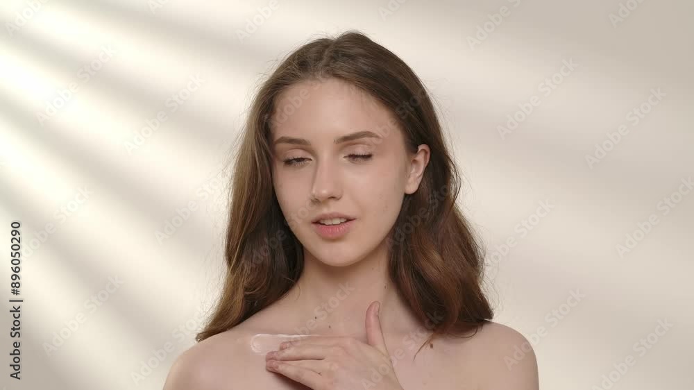 Young woman posing at camera applies body cream moisturizer lotion on skin, isolated on white background. Natural beauty and skin care concept Young woman posing at camera applies body cream moisturizer lotion on skin, isolated on white background. Natural beauty and skin care concept