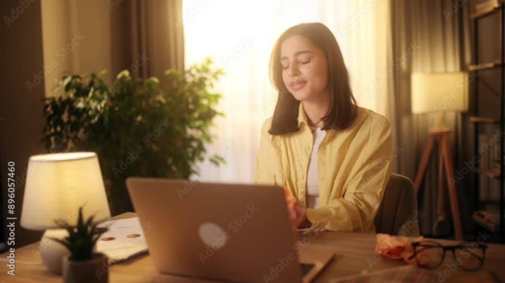 Woman is comfortably working from home, using a laptop and enjoying fruit in a cozy environment, balancing work and relaxation Woman is comfortably working from home, using a laptop and enjoying fruit in a cozy environment, balancing work and relaxation
