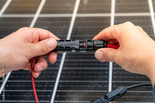 Close up of technician's hands connecting mc4 connectors over the solar panel.