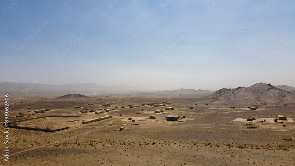 Aerial view of barren desert with remote village and mountains, Gilgit-Baltistan, Pakistan. Aerial view of barren desert with remote village and mountains, Gilgit-Baltistan, Pakistan.