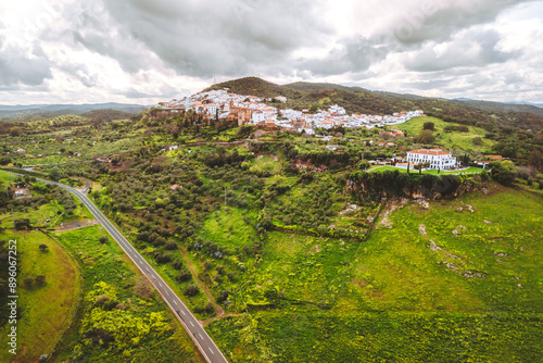 Aerial view of picturesque village nestled in lush green hills with mountain backdrop, Zufre, Huelva, Spain. photo