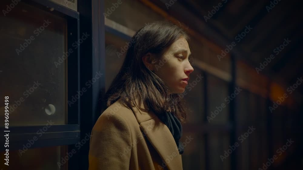 A woman next to a window with city lights, looking thoughtful and introspective A woman next to a window with city lights, looking thoughtful and introspective