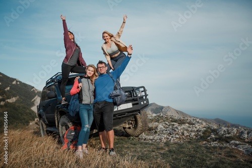 Young happy adult friends on a hike with a car photo