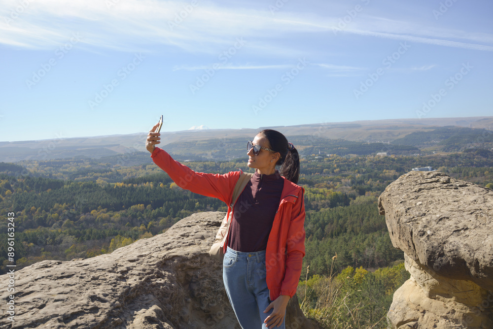 Young beautiful hiker woman taking selfie portrait on the top of mountain - Happy smiling girl using her smartphone - Hiking and climbing cliff