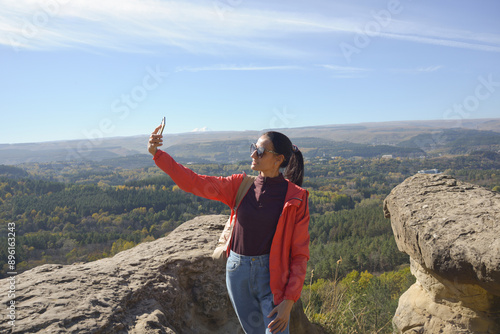 Obraz na płótnie Young beautiful hiker woman taking selfie portrait on the top of mountain - Happy smiling girl using her smartphone - Hiking and climbing cliff w salonie