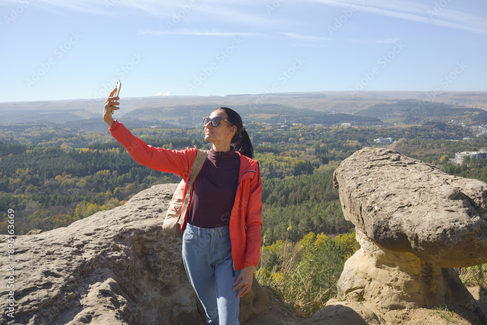 Young beautiful woman traveler taking selfie portrait on mountain top - Happy smiling girl using smartphone - Hiking and climbing rock