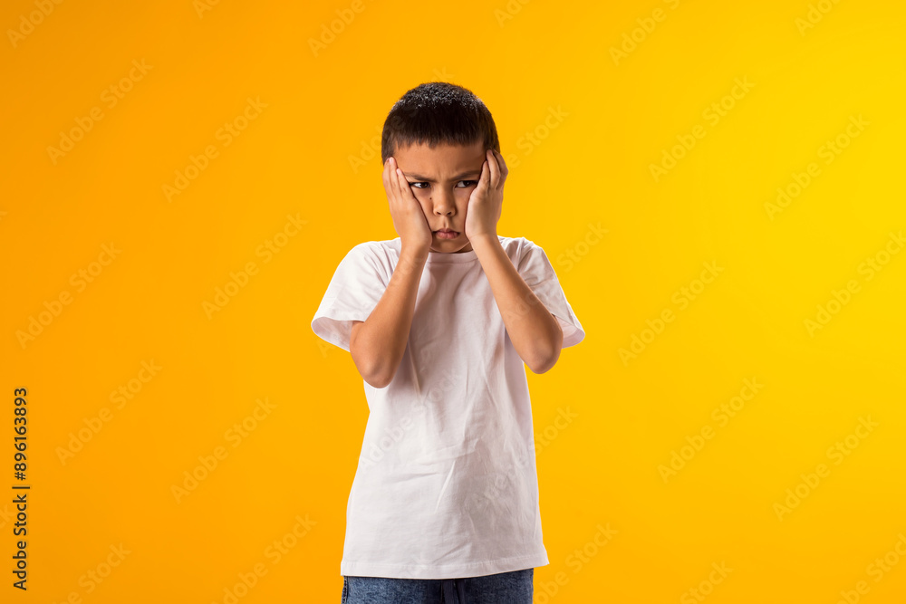 Angry kid boy over yellow background. Emotions and bulling concept Angry kid boy over yellow background. Emotions and bulling concept