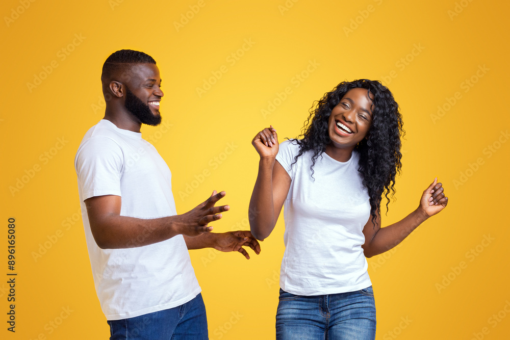 Lovely black couple having good time, dancing and fooling, yellow background Lovely black couple having good time, dancing and fooling, yellow background